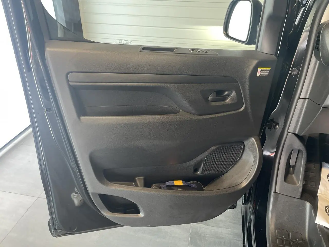 Vue rapprochée de la porte avant gauche noire carbone d'un Opel Vivaro 2025, avec garniture intérieure noire.