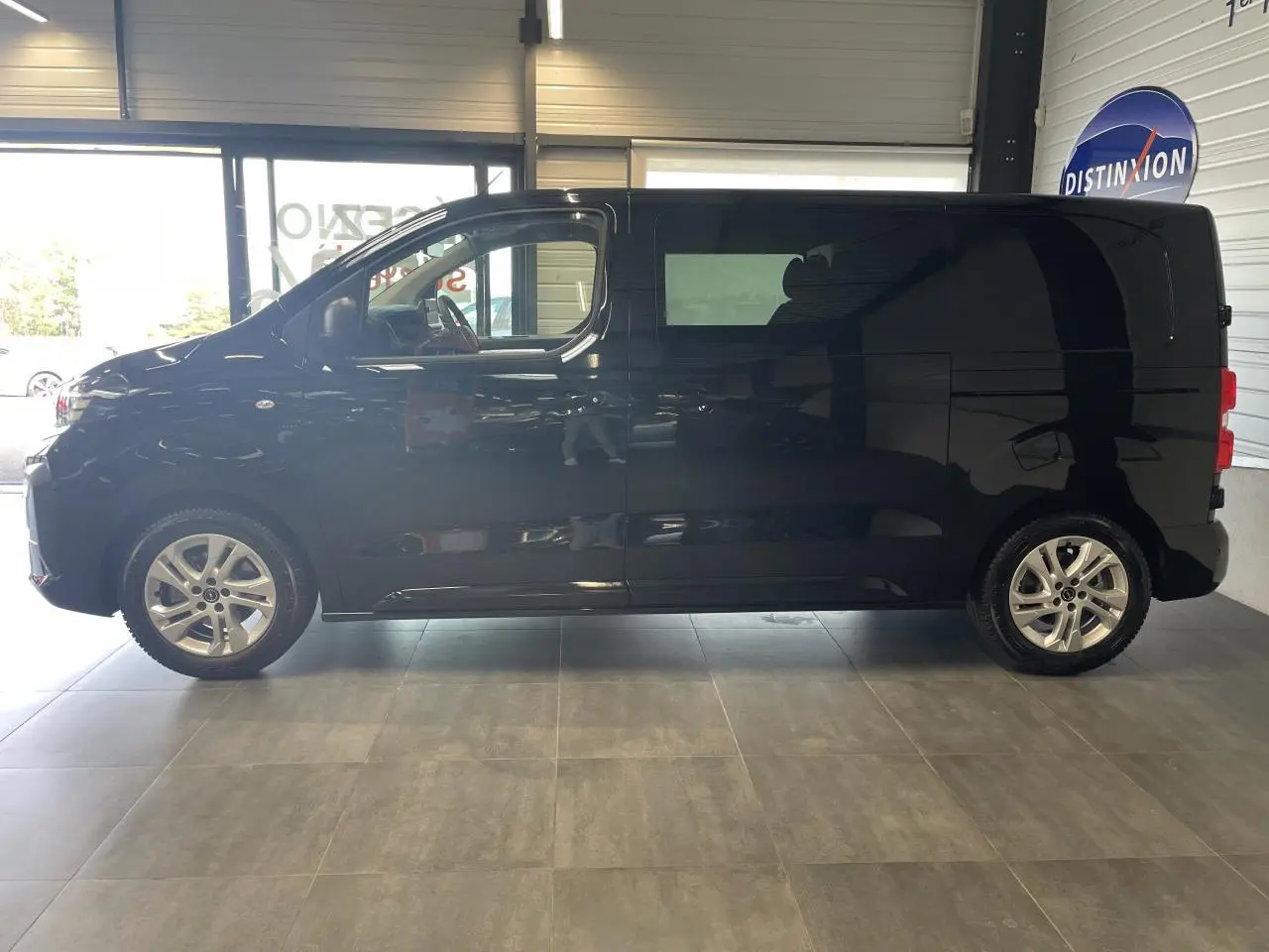 Vue de profil côté gauche d’un Opel Vivaro noir carbone 2025 en intérieur avec jantes alliage argentées.