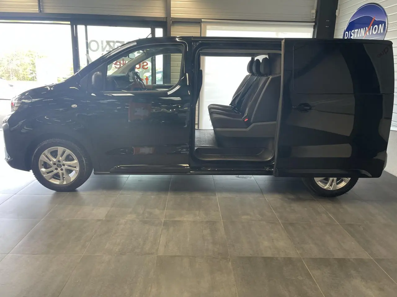 Opel Vivaro noir carbone vu de profil gauche, porte latérale coulissante ouverte révélant trois sièges passagers.