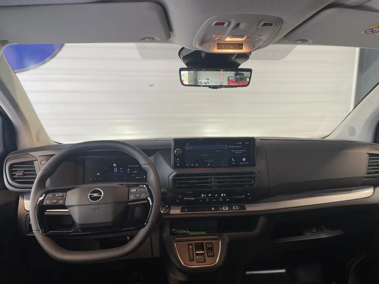 Vue frontale de l’habitacle noir du nouvel Opel Vivaro 2025, avec tableau de bord numérique et écran tactile central.