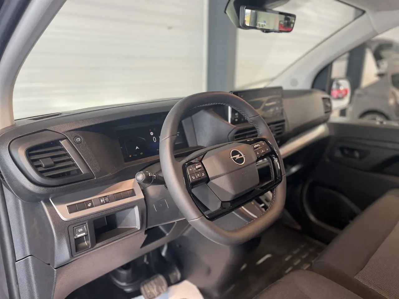 Vue intérieure côté conducteur de l'Opel Vivaro 2025, volant multifonction noir et tableau de bord moderne.