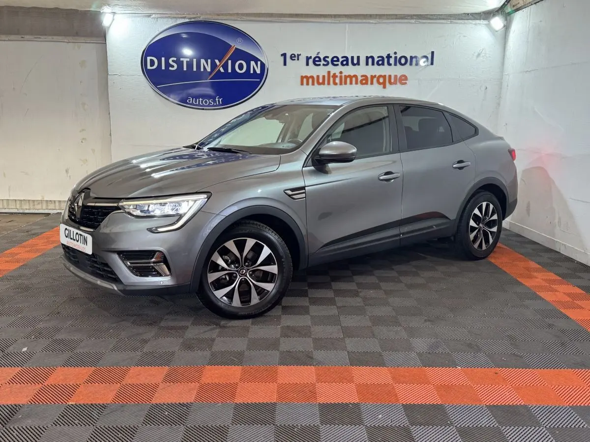 Renault Arkana Business E-TECH 145 gris foncé en 3/4 avant droit, avec jantes bicolores et phares LED allumés.