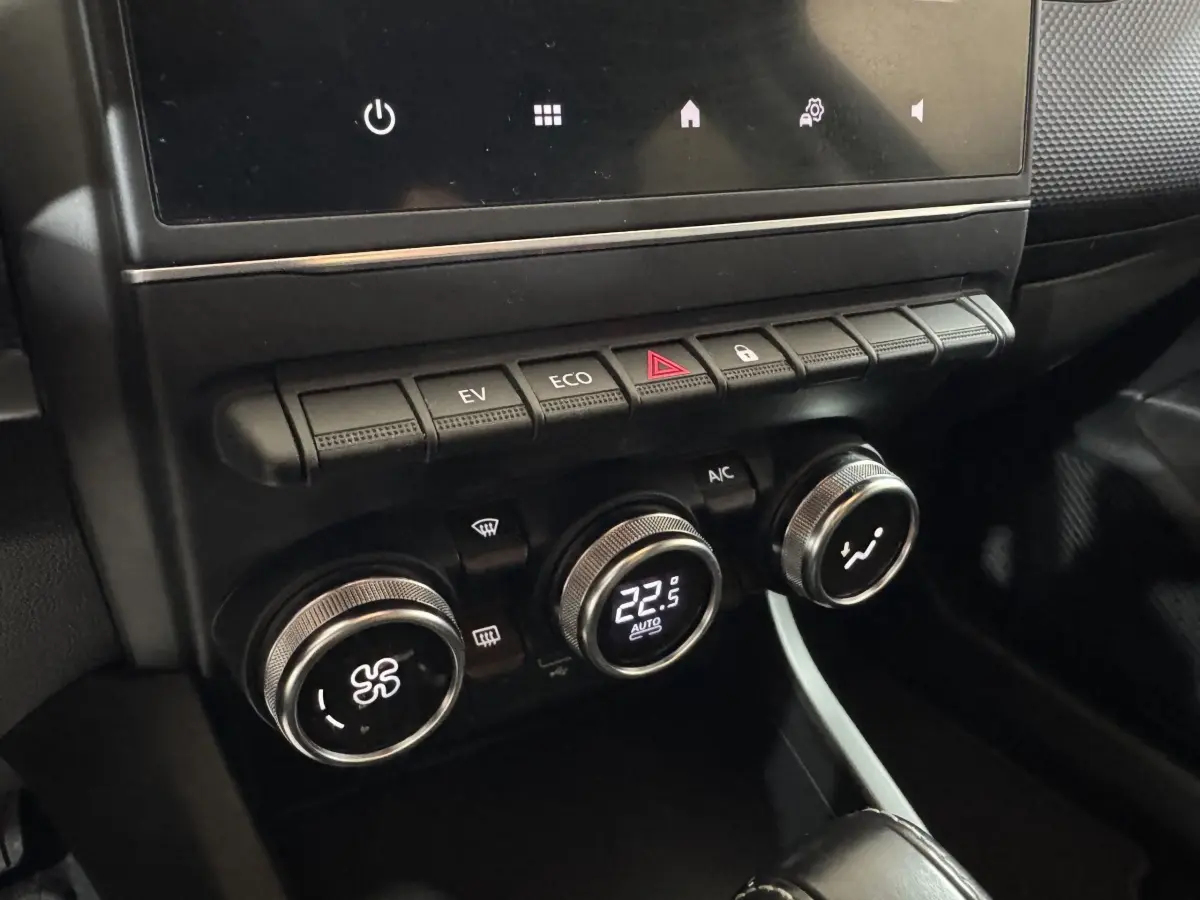 Gros plan sur la console centrale noire du Renault Arkana Business E-TECH 145 avec commandes climatisation et boutons fonctionnels.
