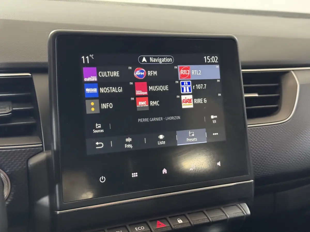 Écran tactile central affichant les stations radio dans l’habitacle d’une Renault Arkana gris foncé, vue de face.