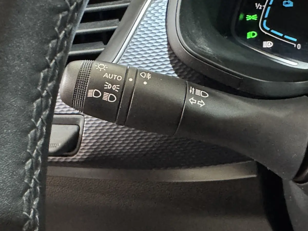 Gros plan sur la commande des phares et clignotants du Renault Arkana Business E-TECH 145, intérieur noir texturé.