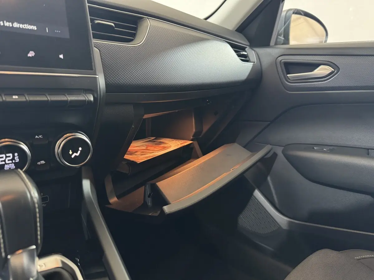 Vue intérieure côté passager du tableau de bord gris foncé et boîte à gants ouverte du Renault Arkana Business E-TECH 145.