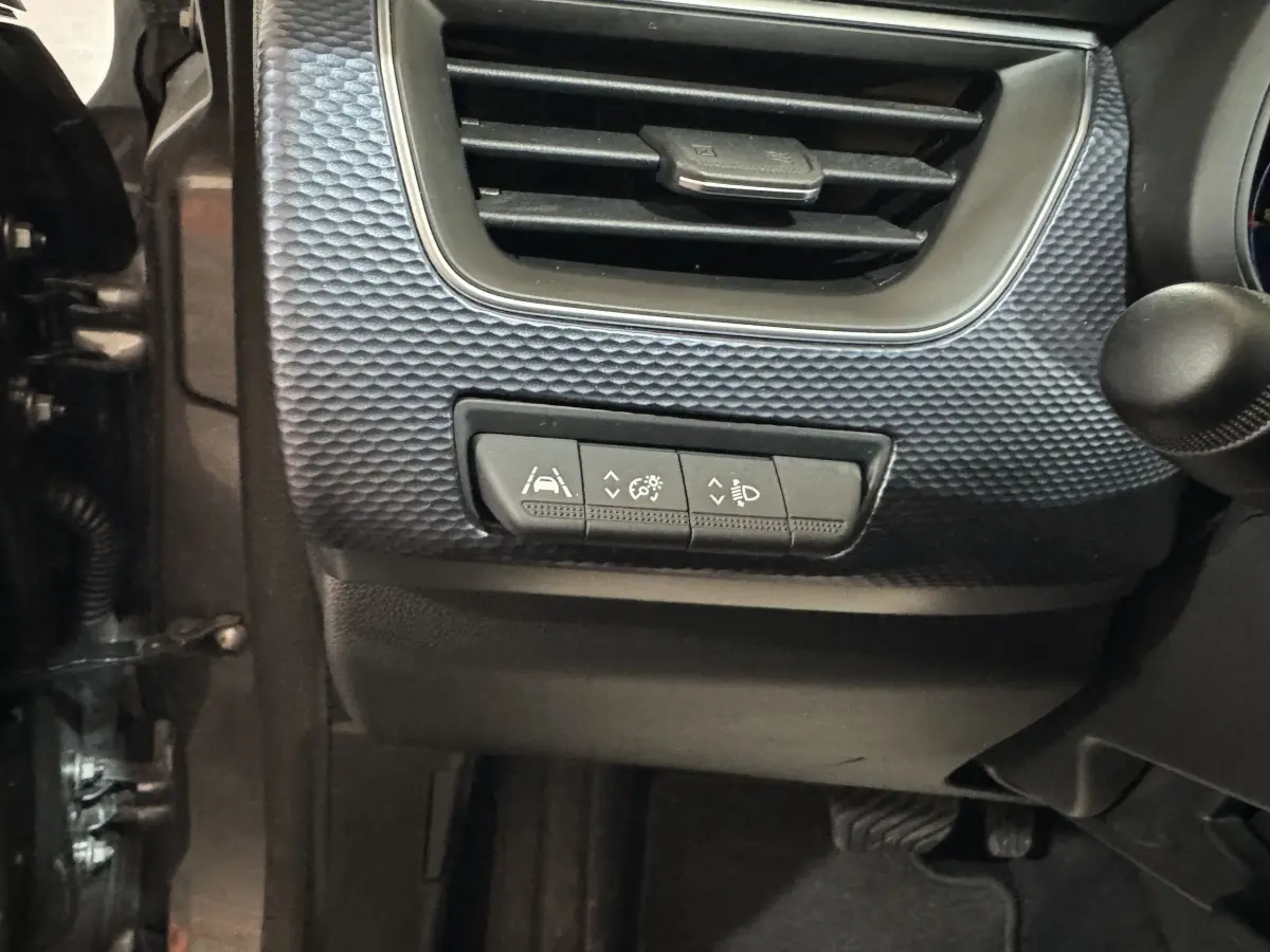 Détail intérieur du tableau de bord côté gauche du Renault Arkana gris foncé, avec commandes d'assistance à la conduite.