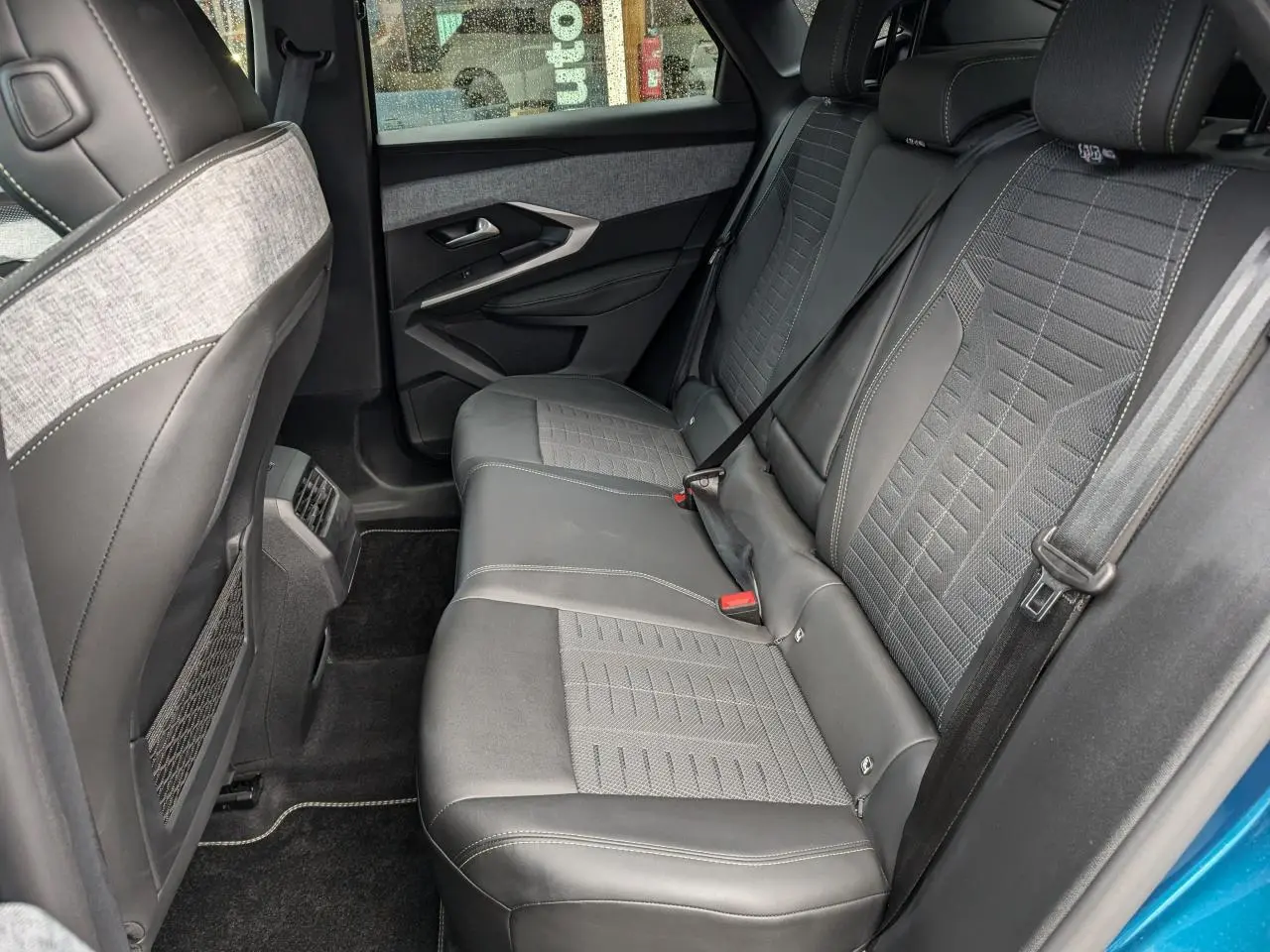 Vue intérieure côté droit sur la banquette arrière gris foncé et tissu chiné du Peugeot 3008 GT bleu métallisé 2025.