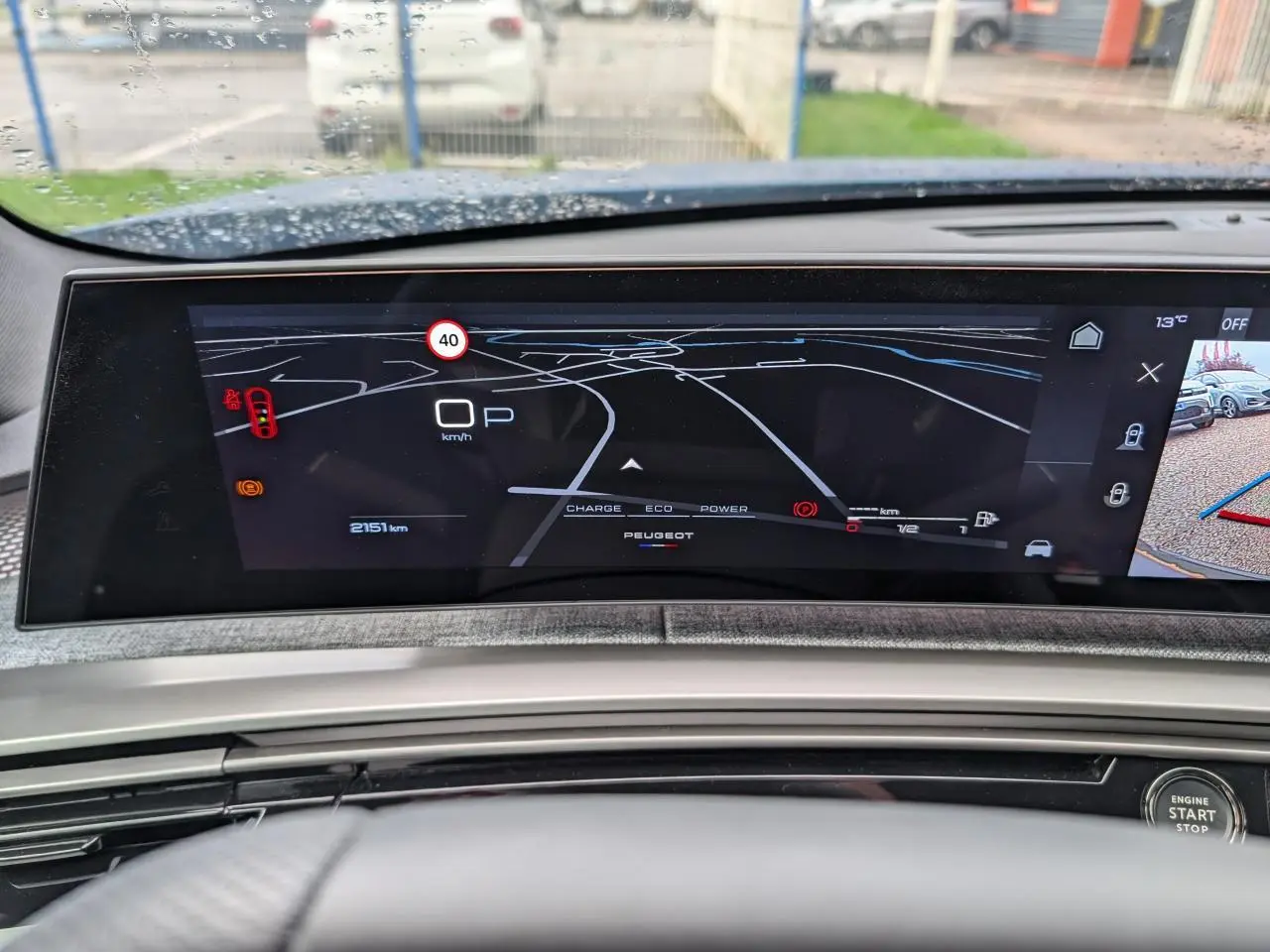 Vue rapprochée du tableau de bord numérique du Peugeot 3008 1.2i Hybrid 2025 avec affichage de navigation et caméra de recul.