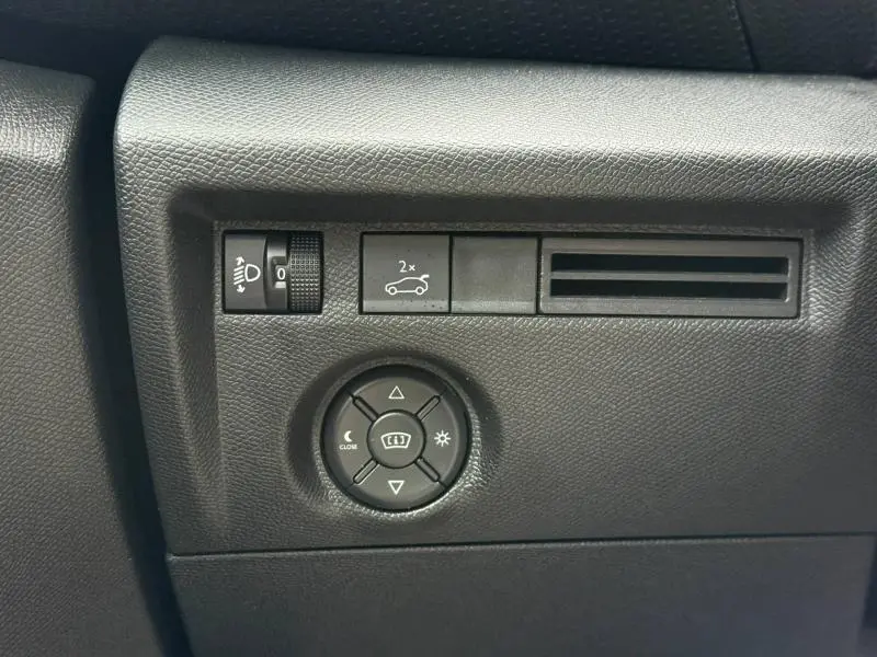 Panneau de commandes intérieures noires du Citroën C4 X 2024 avec réglage des phares et ouverture du coffre.
