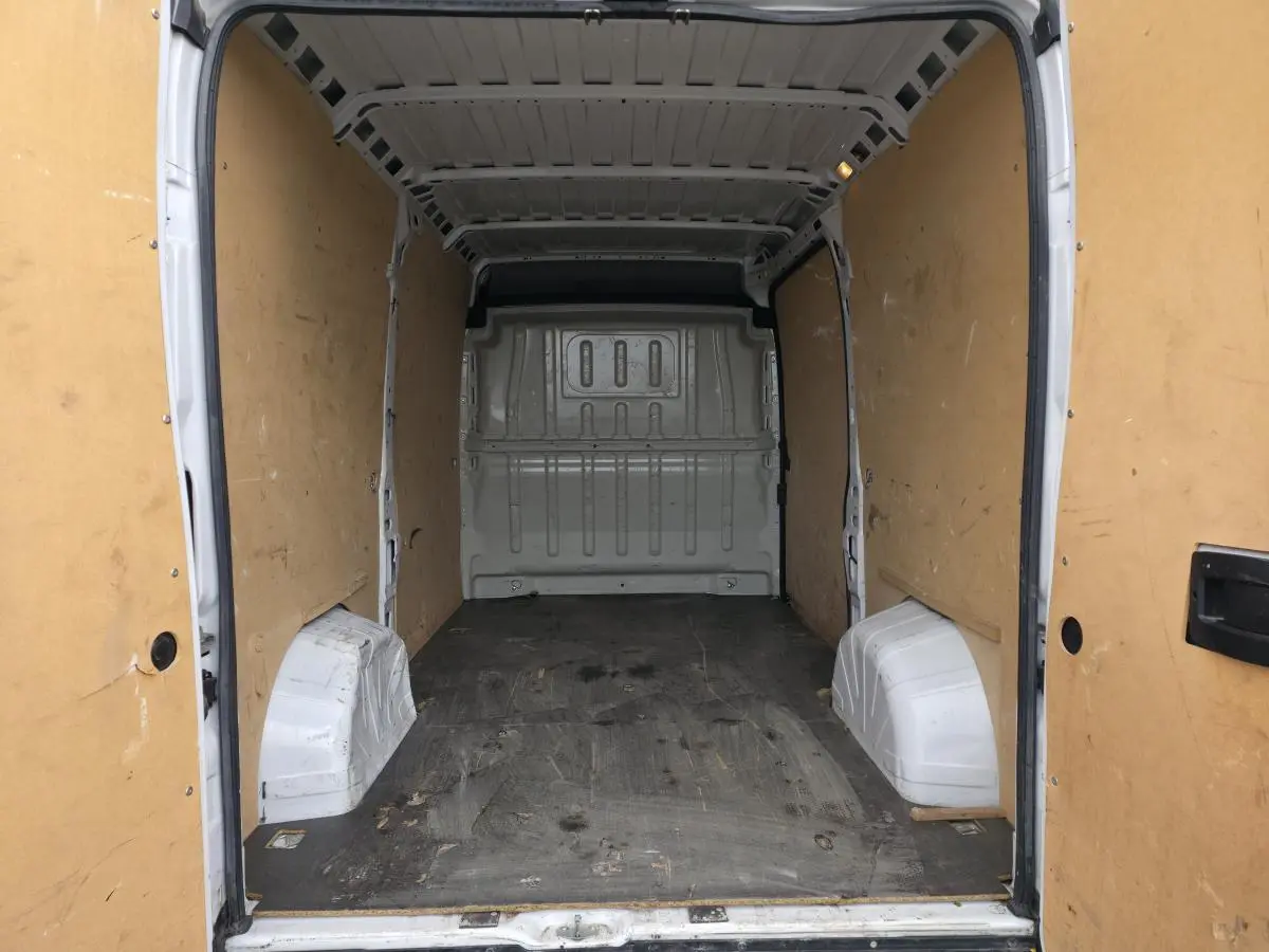 Vue intérieure arrière du fourgon Opel Movano blanc, montrant l'espace de chargement vide avec parois en bois.
