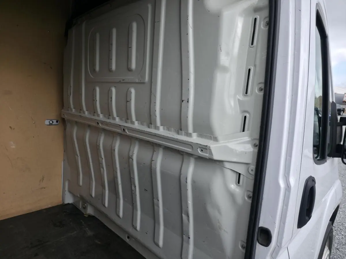 Vue intérieure du fourgon Opel Movano blanc, montrant la cloison pleine tôlée séparant la cabine et l'espace de chargement.