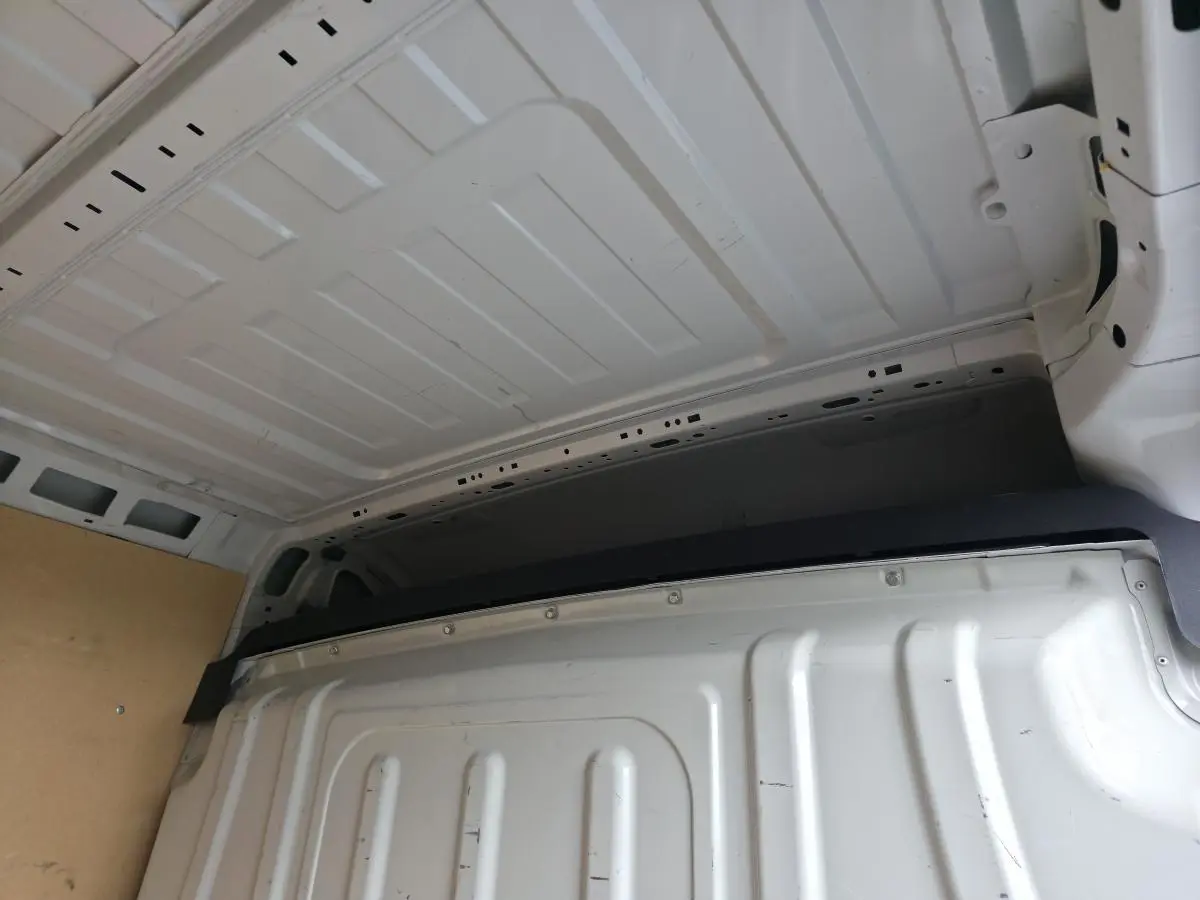 Vue intérieure du fourgon Opel Movano blanc montrant la cloison pleine tôlée de séparation et le plafond métallique.