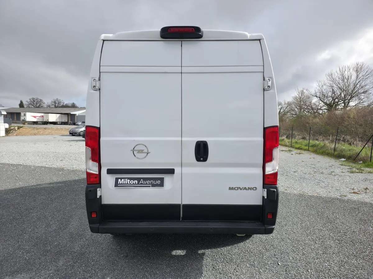 Vue arrière d'un fourgon Opel Movano blanc avec portes battantes et feux rouges verticaux.