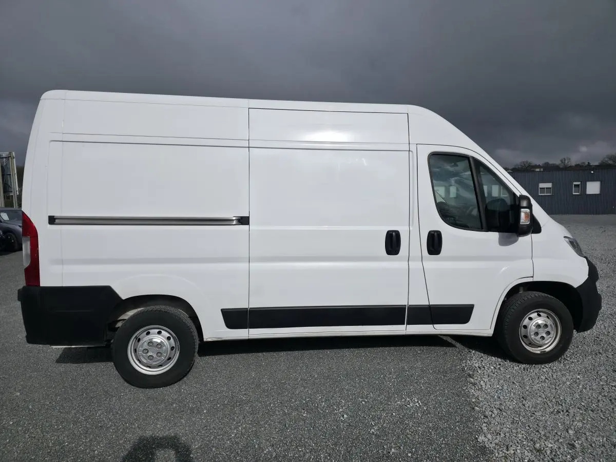 Vue de profil droit de l'Opel Movano Fourgon blanc 2022 avec portes latérales coulissantes et jantes tôles grises.
