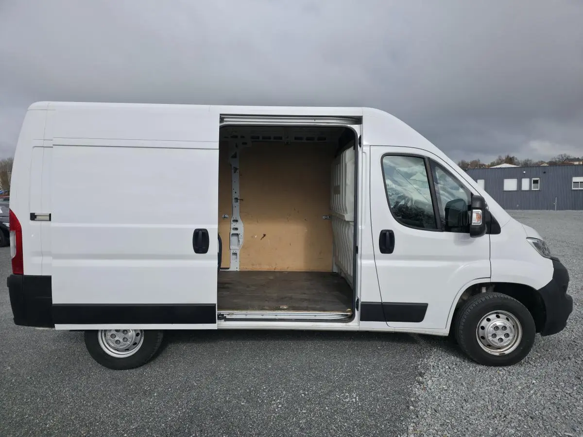 Vue latérale droite d’un Opel Movano Fourgon blanc 2022 avec porte coulissante ouverte montrant l’espace de chargement vide.