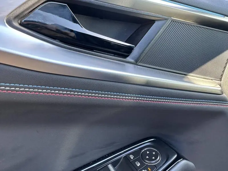 Détail de la porte intérieure côté conducteur de la Renault Rafale bleu sommet, avec surpiqûres tricolores et commandes électriques.