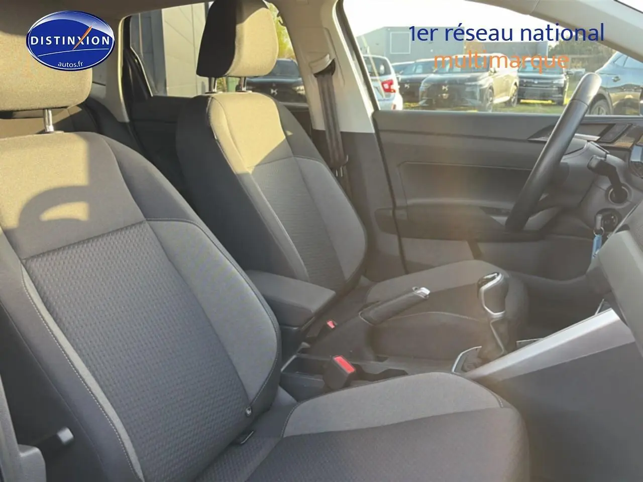 Vue intérieure côté droit de la Volkswagen Polo gris, montrant les sièges avant et la console centrale avec levier de vitesse manuel.
