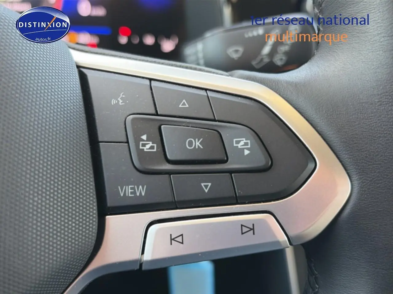 Gros plan sur les commandes multifonctions du volant cuir de la Volkswagen Polo gris, avec boutons de navigation et audio.