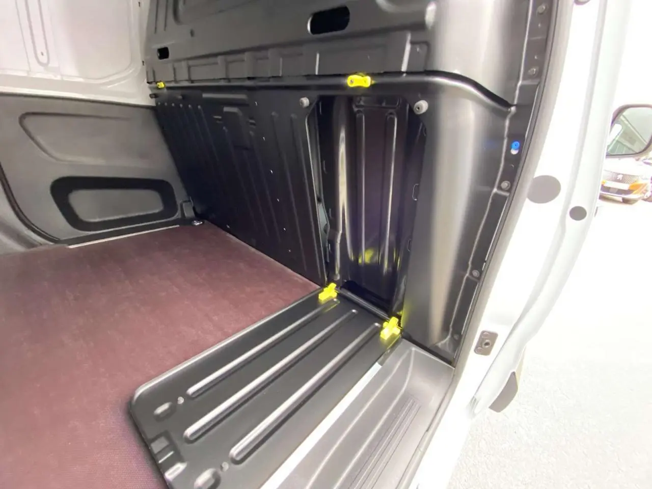 Vue intérieure du compartiment de chargement arrière droit du Citroën Berlingo blanc avec plancher bois et renforts noirs.