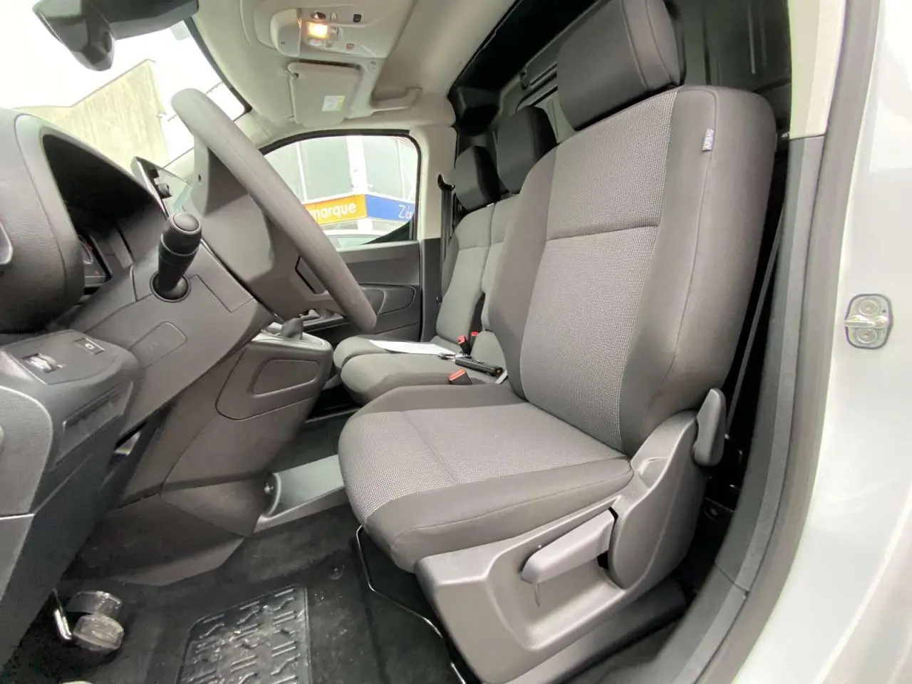 Vue intérieure côté conducteur du Citroën Berlingo blanc 2026, montrant les sièges gris et le tableau de bord.