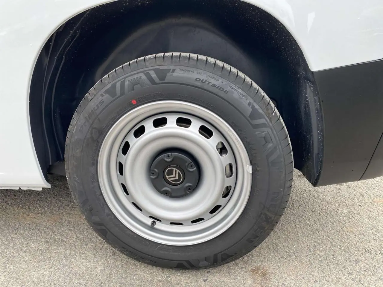 Gros plan sur la roue arrière droite d’un Citroën Berlingo blanc avec jante acier grise et logo Citroën central.