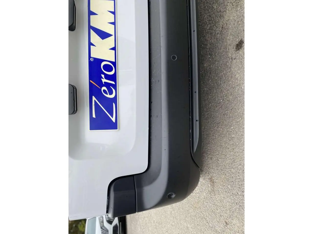 Gros plan sur le pare-chocs arrière noir et la partie basse blanche du Citroën Berlingo 2026, avec plaque "Zéro KM".