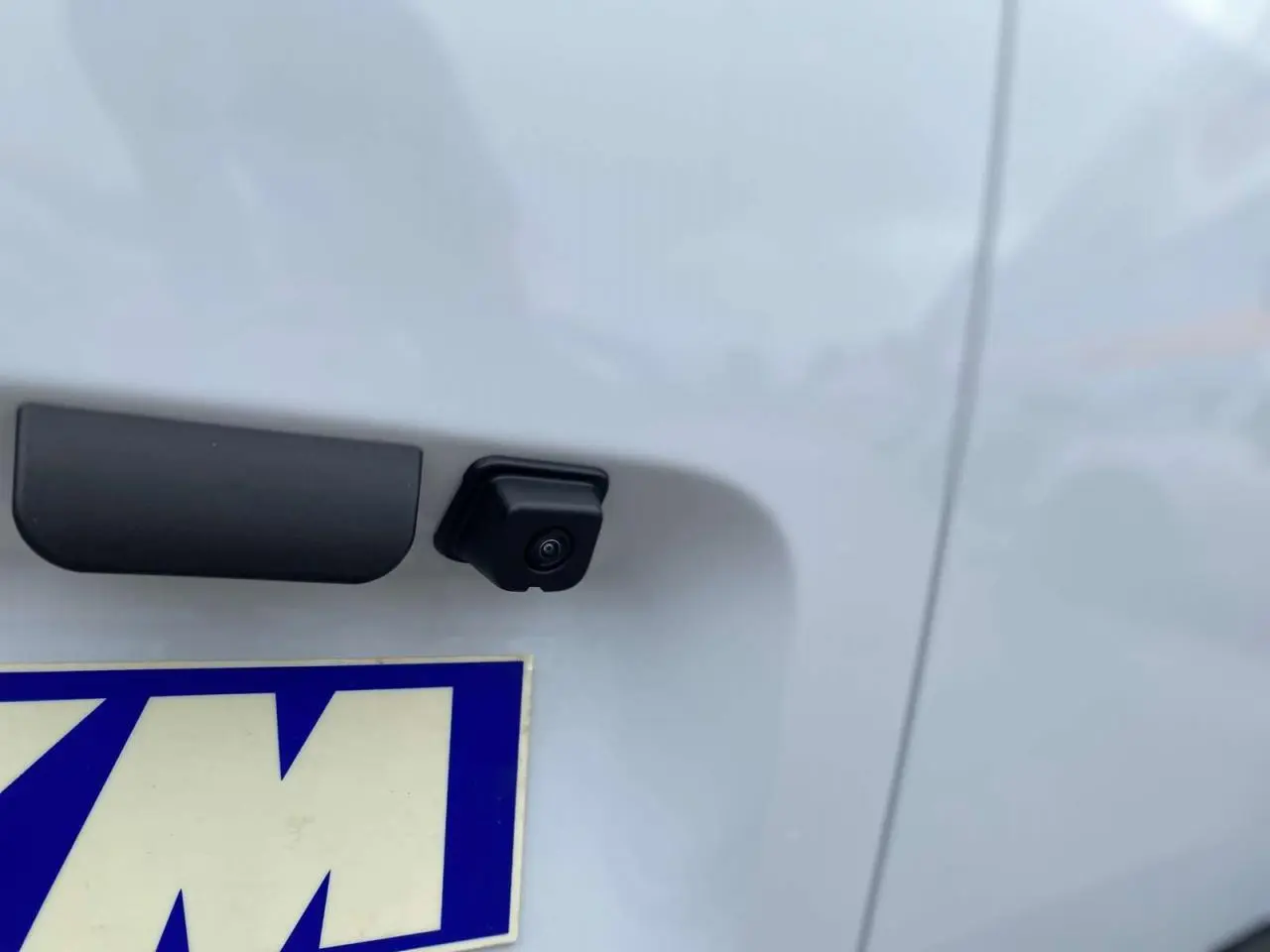 Gros plan sur la caméra de recul noire intégrée au hayon arrière blanc du Citroën Berlingo 2026.