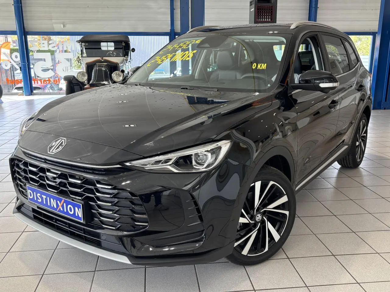 Vue 3/4 avant du MG ZS 1.5 Hybrid+ noir métallisé avec jantes alliage et calandre imposante en showroom.