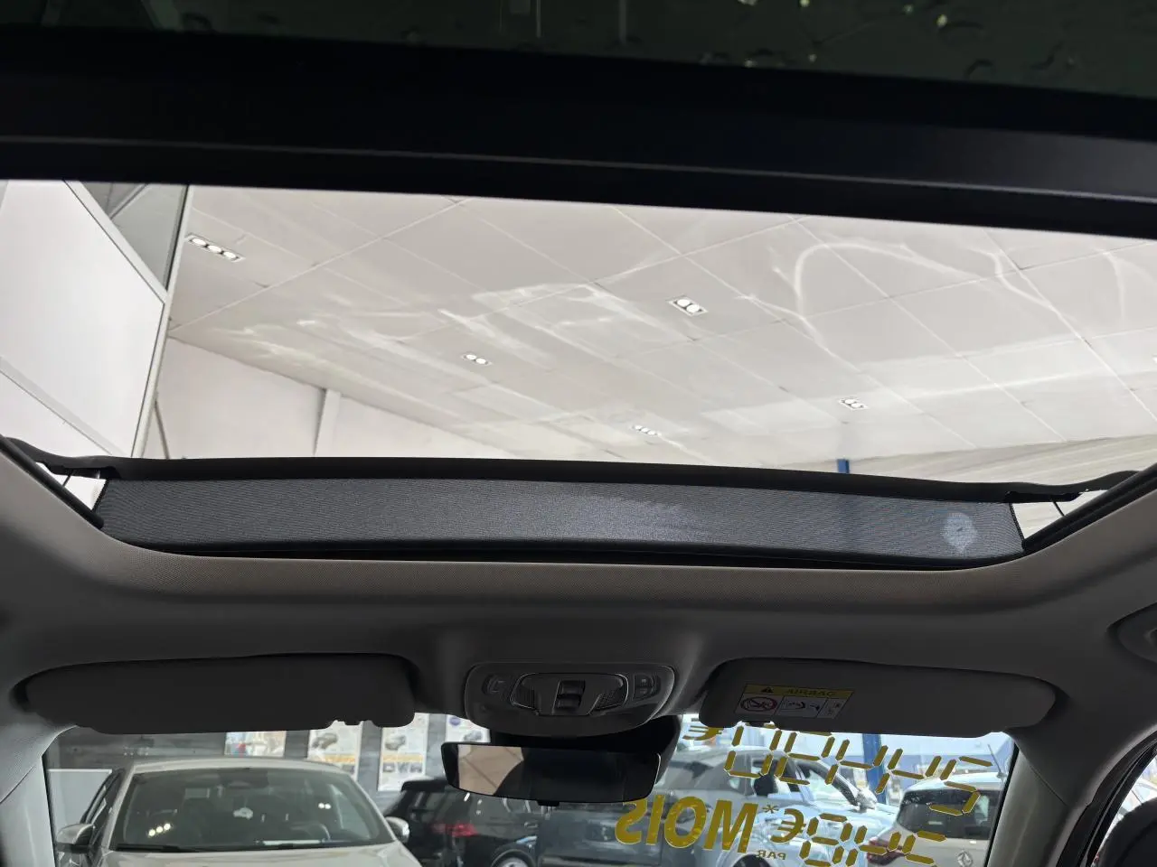Vue intérieure du toit panoramique ouvrant du MG MOTOR ZS 1.5 Hybrid+ noir, avec commandes et pare-soleil visibles.