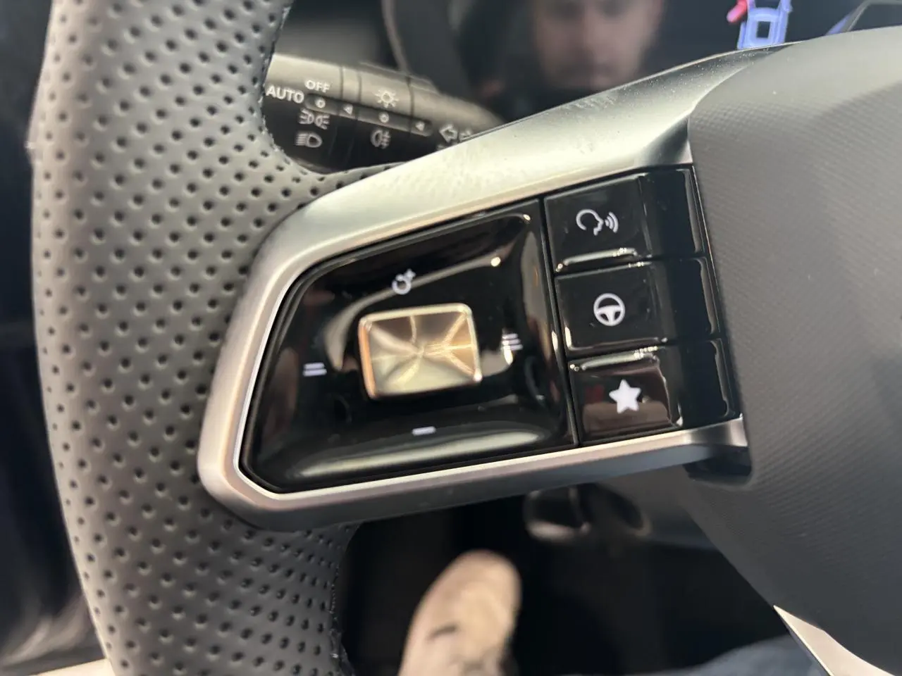 Gros plan sur les commandes multifonctions gauche du volant perforé noir du MG Motor ZS 1.5 Hybrid+ 2026.