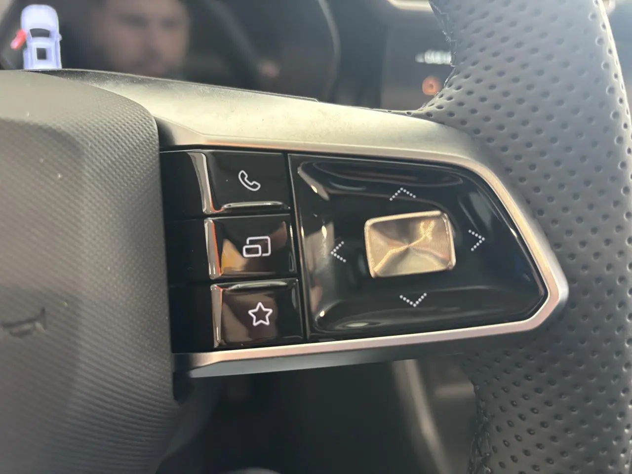 Gros plan sur les commandes gauche du volant perforé du MG Motor ZS 1.5 Hybrid+ noir, boutons lumineux.
