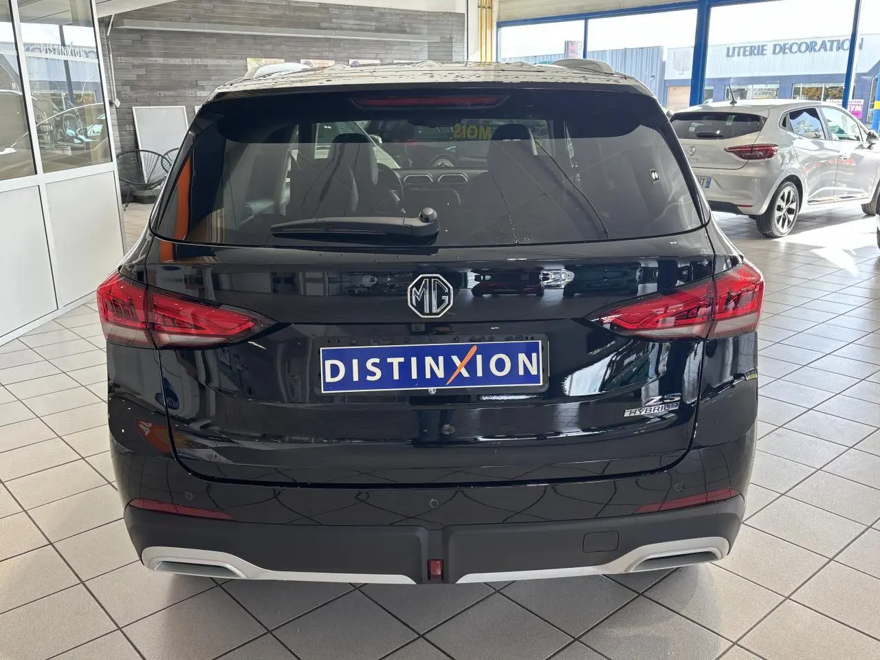 Vue arrière d'un MG Motor ZS 1.5 Hybrid+ noir, avec feux LED et logo MG visible en concession.