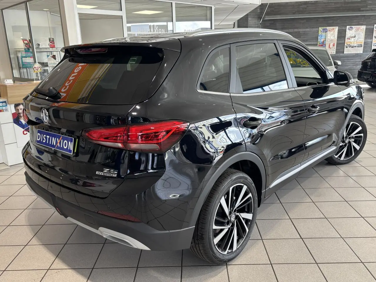 Vue 3/4 arrière droite du MG ZS Hybrid+ noir avec jantes alliage 18 pouces et vitres surteintées en showroom.