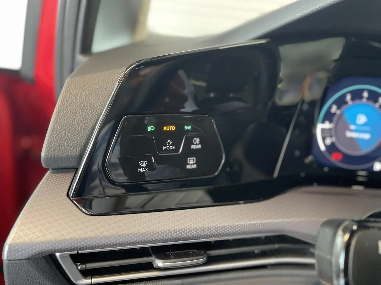 Panneau de commandes des feux et éclairages sur tableau de bord d'une Volkswagen Golf rouge métal, intérieur beige.