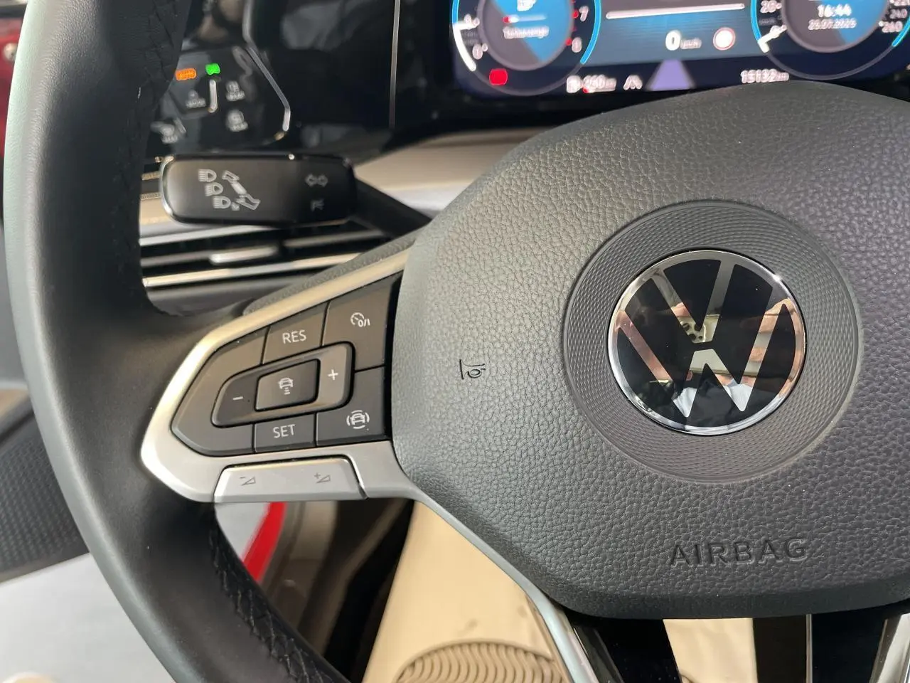 Gros plan sur le volant multifonction noir de la Volkswagen Golf 1.5 TSI Active rouge métal, avec tableau de bord digital en arrière-plan.