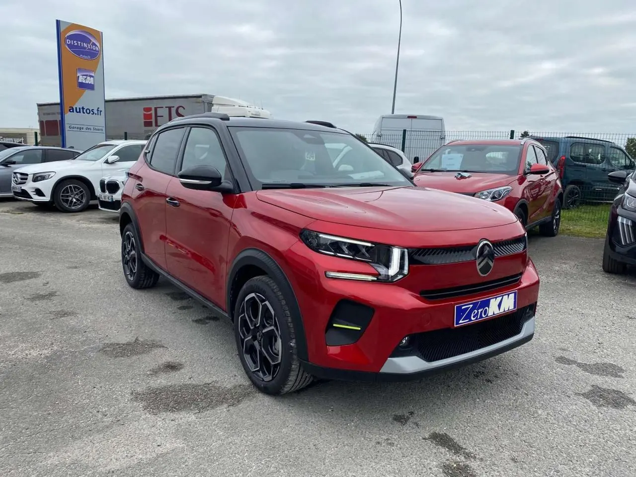 SUV Citroën C3 Turbo 100 CH rouge Elixir avec toit noir, vu en 3/4 avant droit sur parking extérieur.