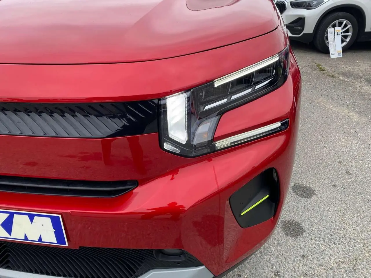 Gros plan sur l'avant droit d'une Citroën C3 rouge Elixir avec toit noir, mettant en valeur son phare LED distinctif.