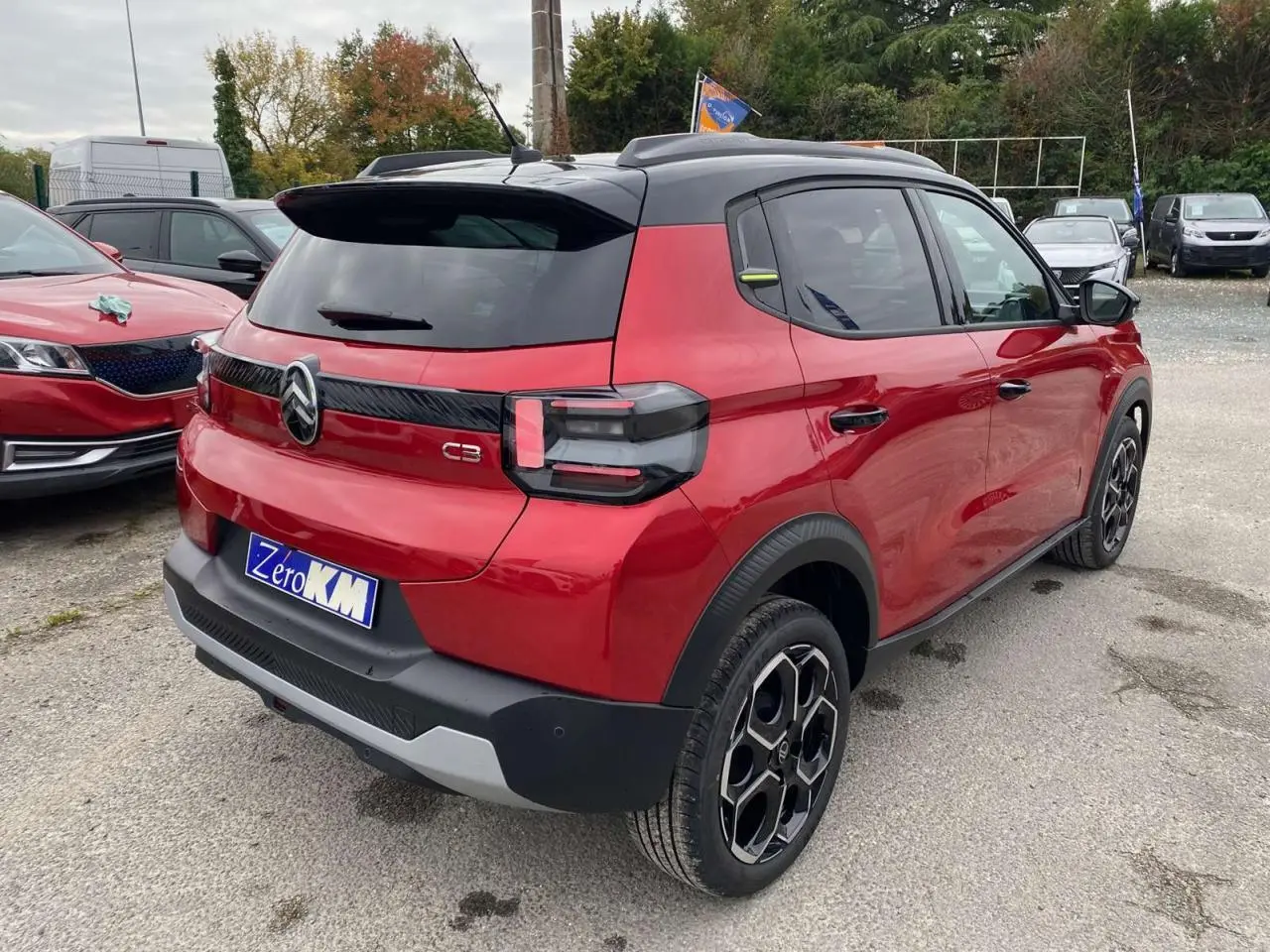Vue 3/4 arrière droite d'une Citroën C3 rouge Elixir au toit noir avec jantes alliage et vitres arrière surteintées.