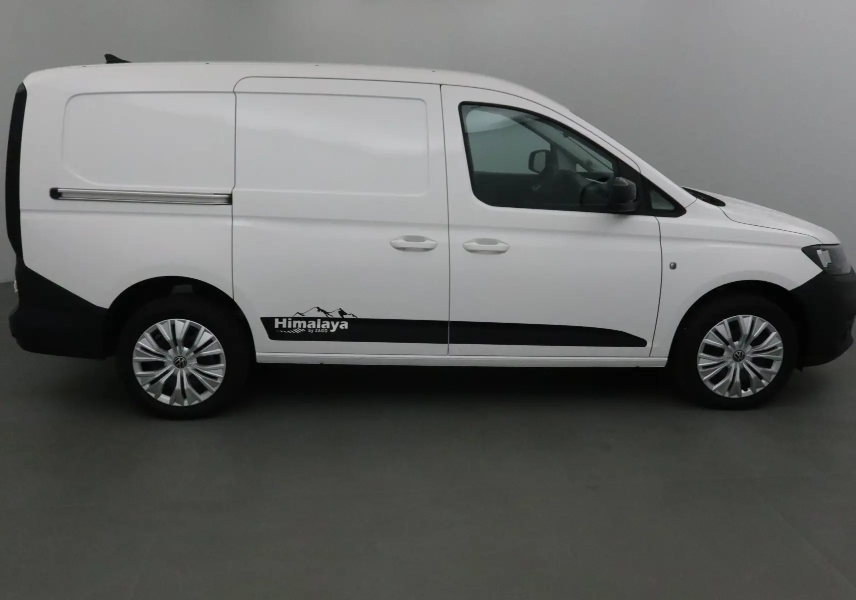 Vue latérale droite d'un Volkswagen Caddy Maxi blanc avec logo Himalaya et jantes argentées.