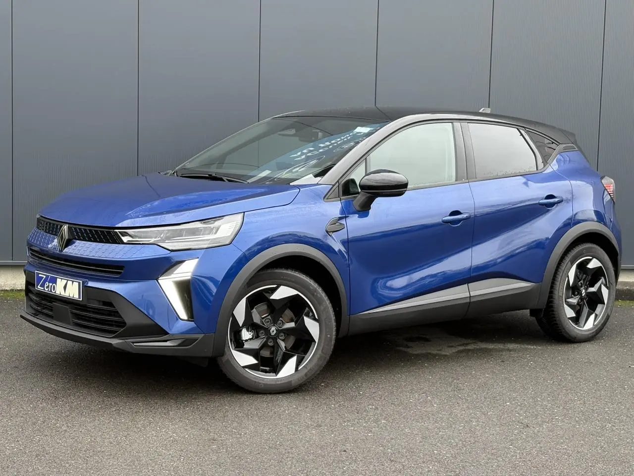 Renault Captur 2025 bleu Iron en 3/4 avant droit avec toit noir et jantes aluminium 18 pouces biton.