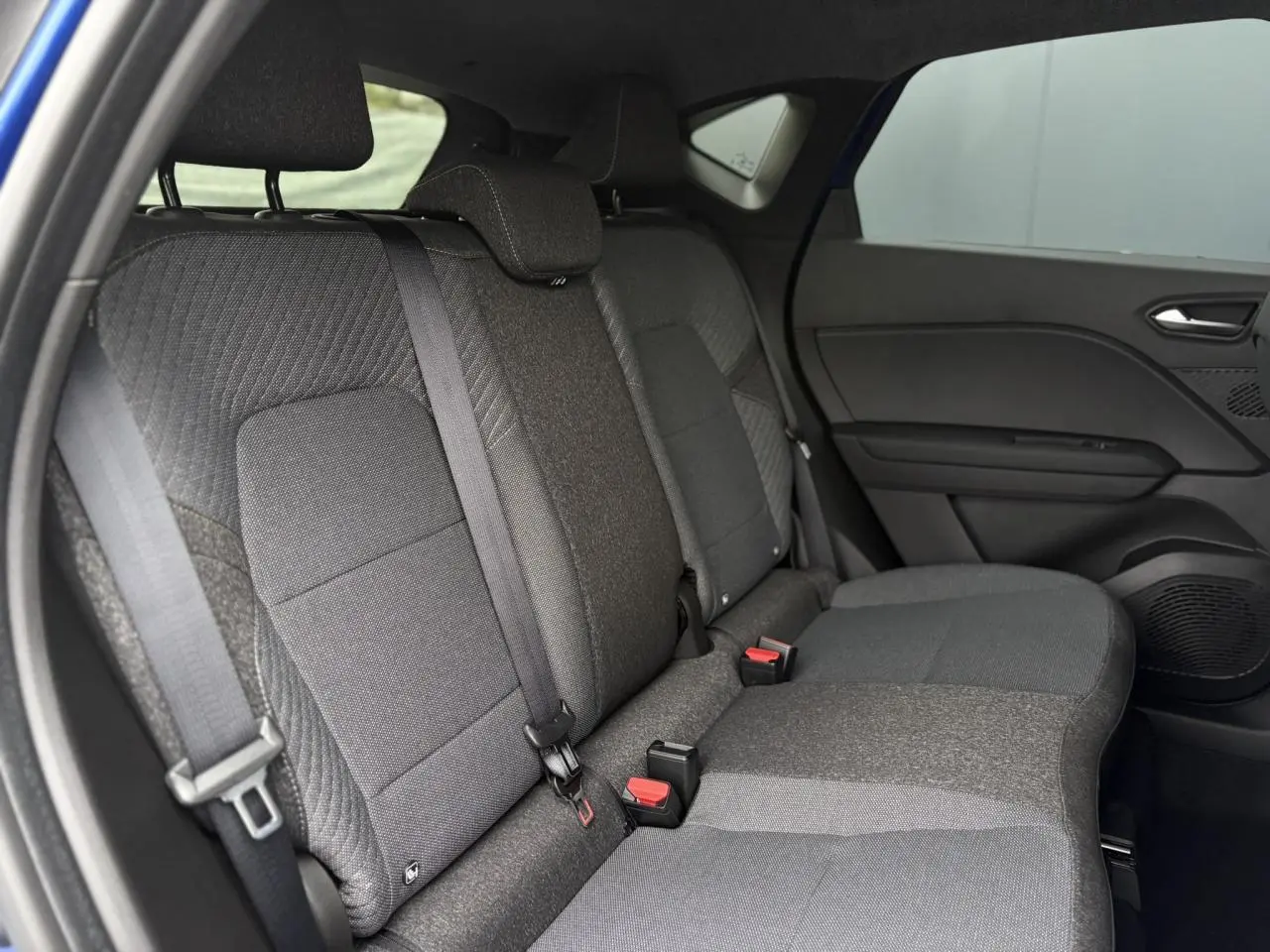 Vue latérale intérieure des sièges arrière gris foncé du Renault Captur 2025, avec ceinture de sécurité et porte côté droit visible.