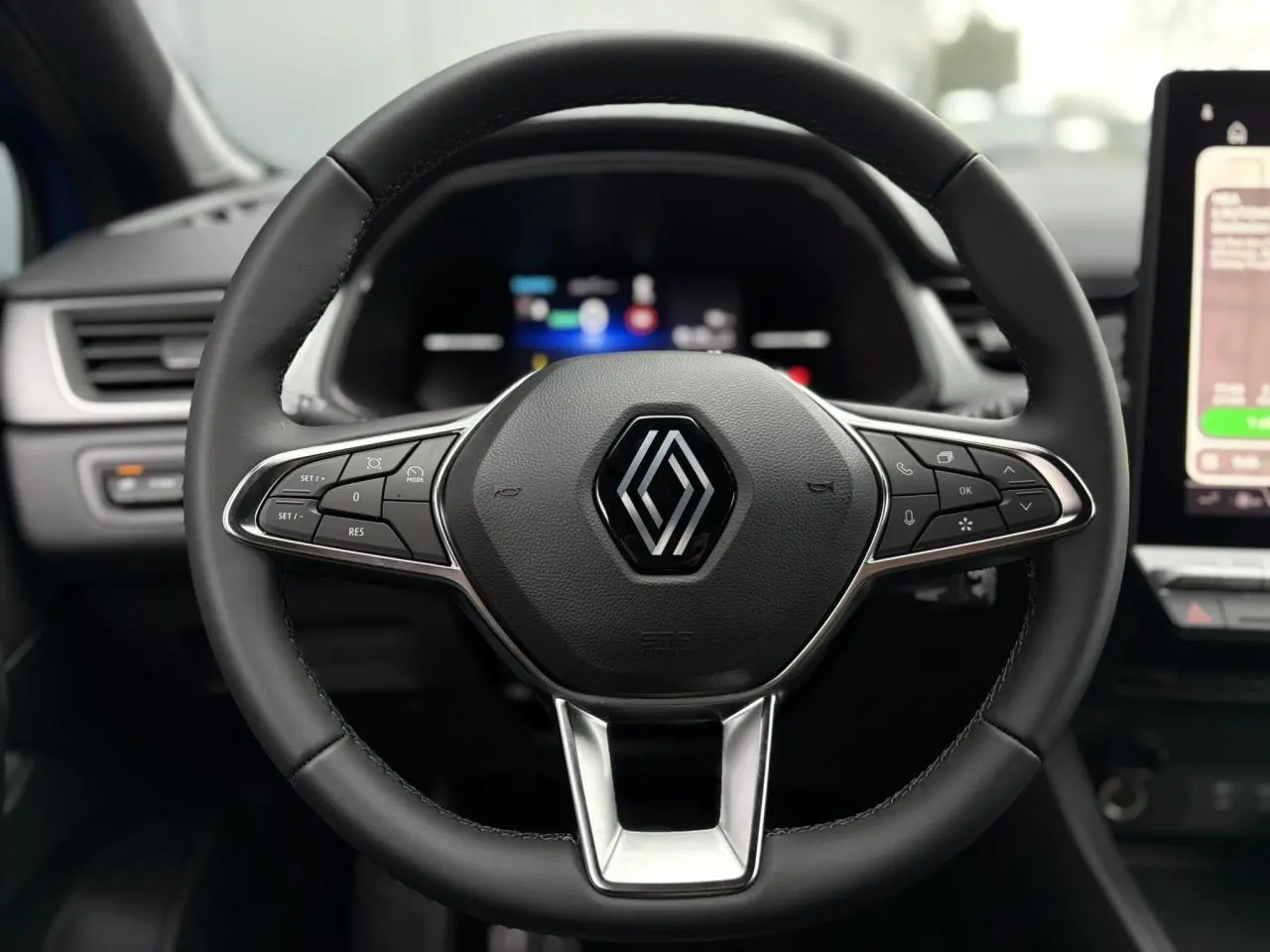 Gros plan sur le volant noir du Renault Captur 2025 avec commandes intégrées et logo central chromé.