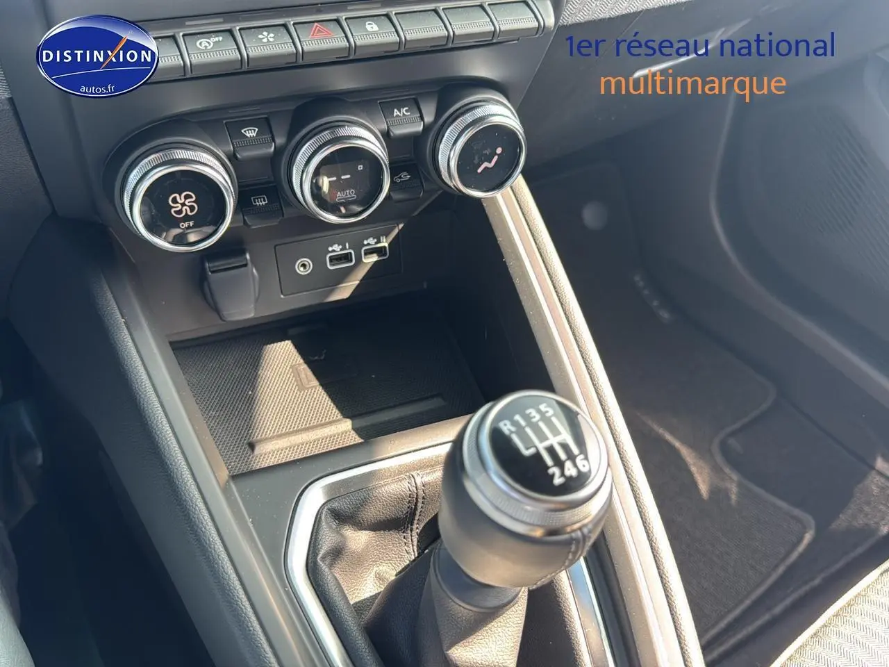 Gros plan sur la console centrale noire de la Renault Clio V avec levier de vitesse manuel et commandes de climatisation.