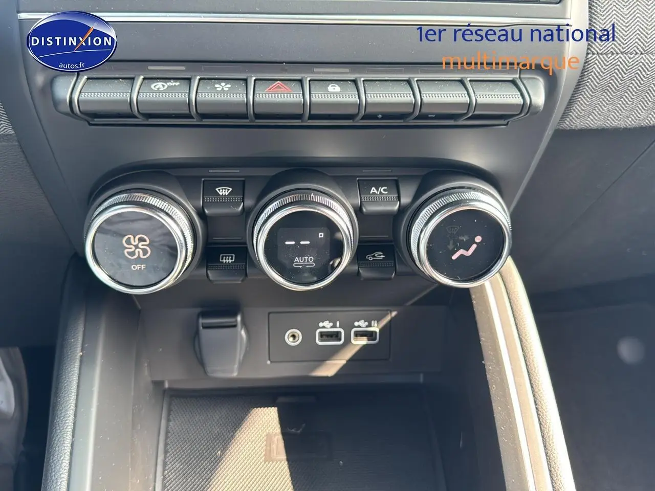Détail de la console centrale noire de la Renault Clio V avec commandes de climatisation et ports USB visibles.