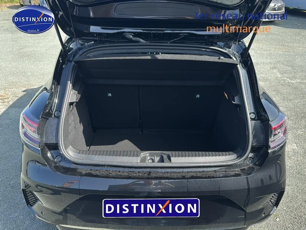 Coffre ouvert vu de l'arrière d'une Renault Clio V noire, avec feux arrière à LED visibles.