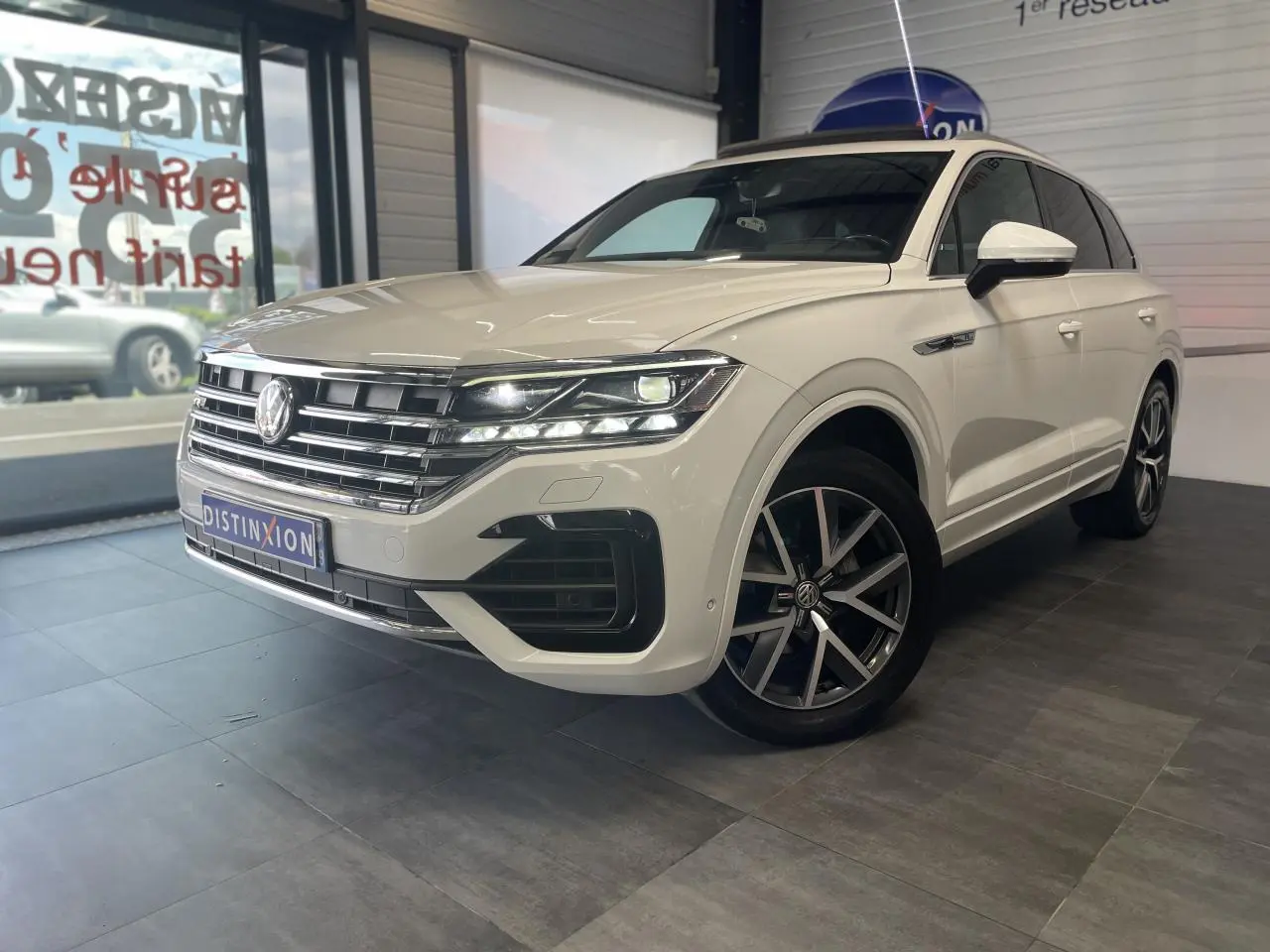 Volkswagen Touareg blanc en 3/4 avant droit avec jantes alliage 20 pouces et calandre chromée showroom intérieur.