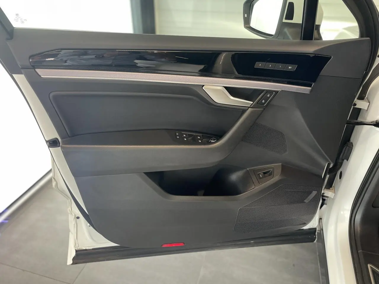 Vue intérieure côté gauche de la porte avant blanche du Volkswagen Touareg 2019 avec garniture noire et inserts laqués.