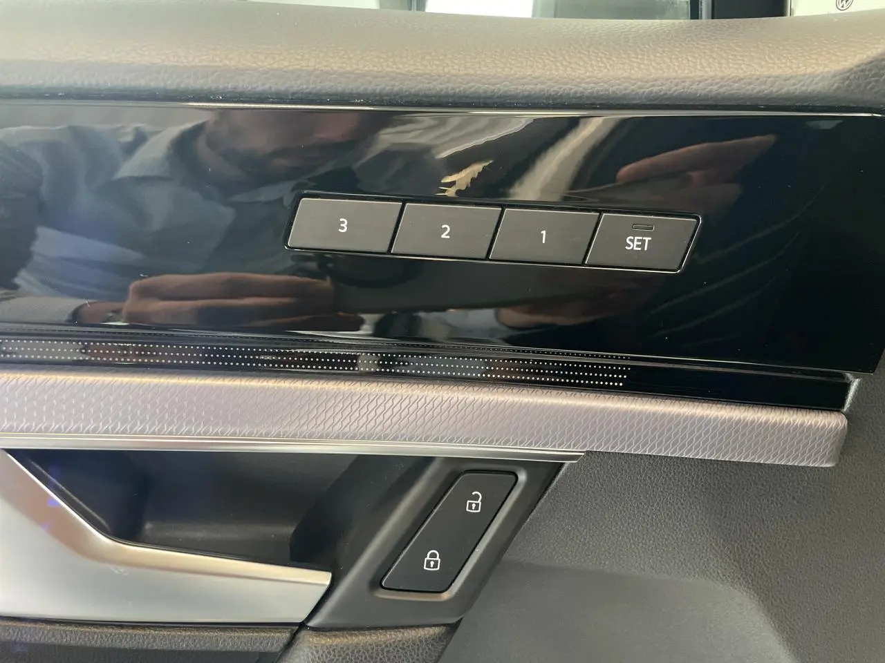 Détail intérieur montrant les boutons de mémorisation des sièges et les commandes de verrouillage sur la porte côté conducteur.