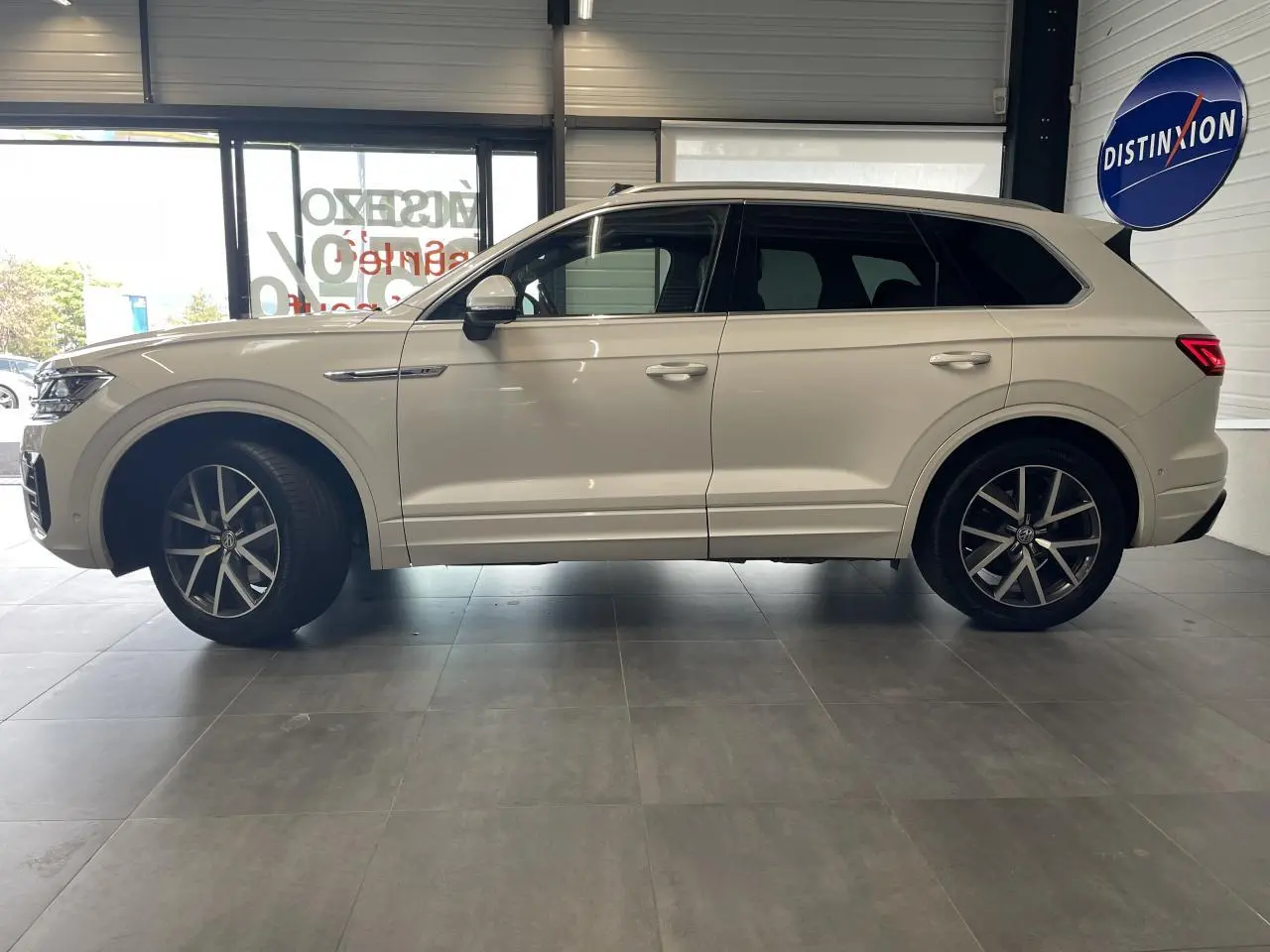 Vue de profil côté gauche d’un Volkswagen Touareg blanc 2019 avec jantes alliage 20 pouces et vitres sur-teintées.